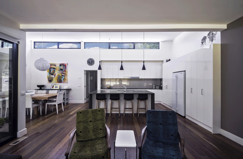 Cette image montre une salle de séjour minimaliste de taille moyenne et ouverte avec un mur blanc, parquet foncé et un sol marron.