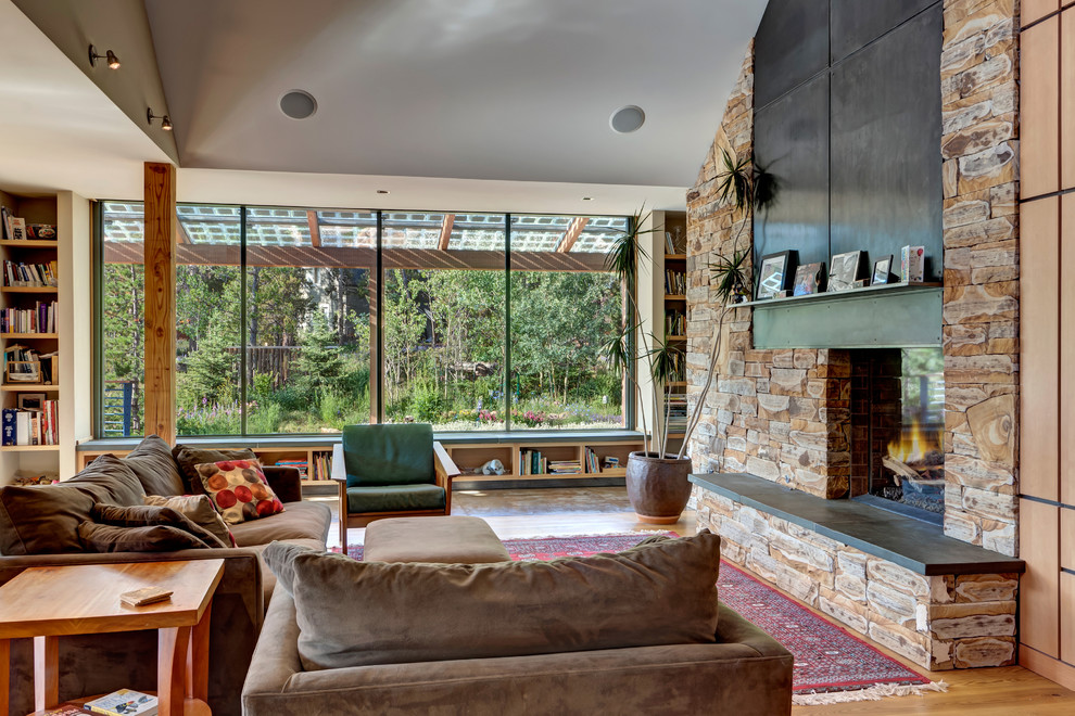 Foto de sala de estar con biblioteca abierta rural con suelo de madera en tonos medios, todas las chimeneas, marco de chimenea de piedra y alfombra