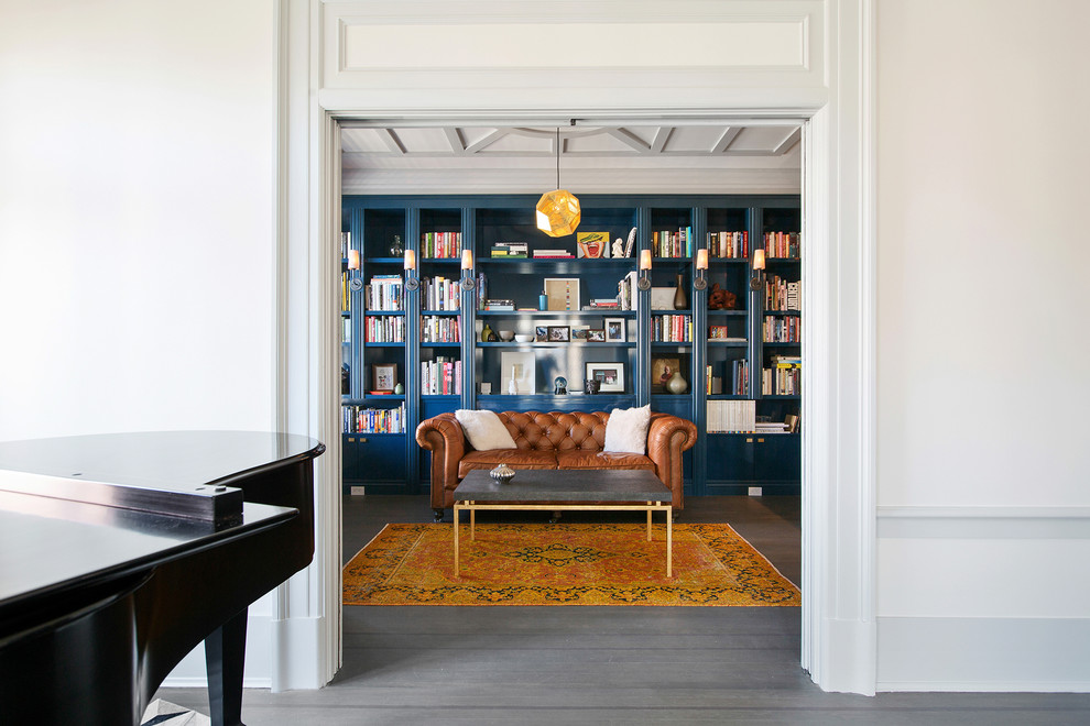 Foto de sala de estar con biblioteca abierta clásica grande con paredes azules, suelo de madera en tonos medios y suelo gris