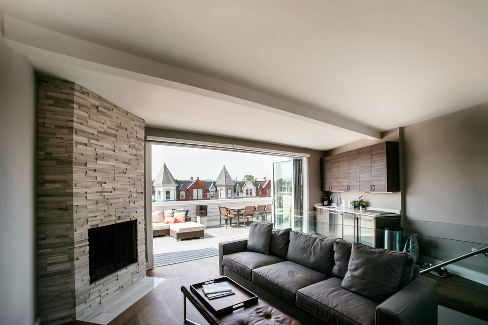 Cette image montre une salle de séjour minimaliste ouverte avec un bar de salon, un mur beige, parquet foncé, une cheminée d'angle et un manteau de cheminée en pierre.