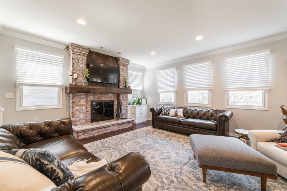Inspiration for a medium sized country enclosed games room in Chicago with beige walls, a standard fireplace, a brick fireplace surround, a wall mounted tv and brown floors.