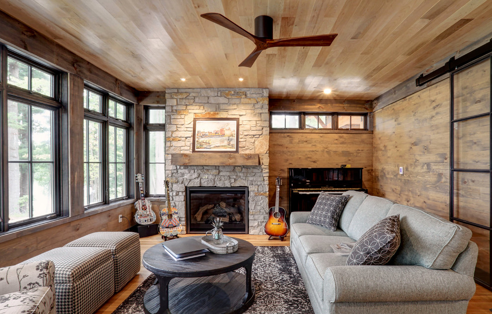 Foto de sala de estar con rincón musical rústica con paredes marrones, suelo de madera en tonos medios, todas las chimeneas, marco de chimenea de piedra, suelo marrón y alfombra