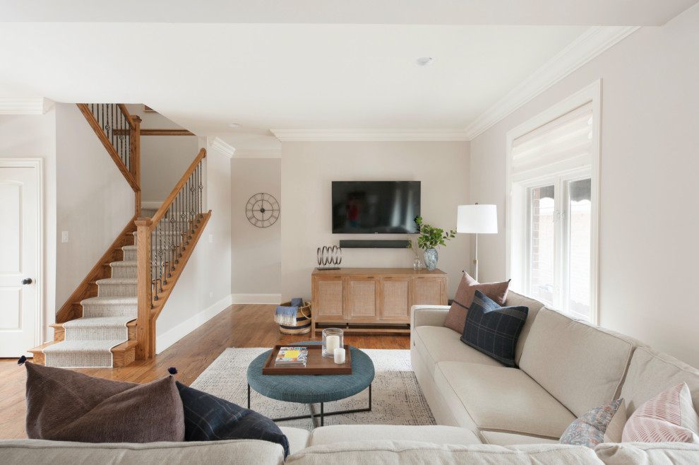 Cette image montre une salle de séjour traditionnelle ouverte avec un mur gris, un sol en bois brun, un téléviseur fixé au mur et un sol marron.