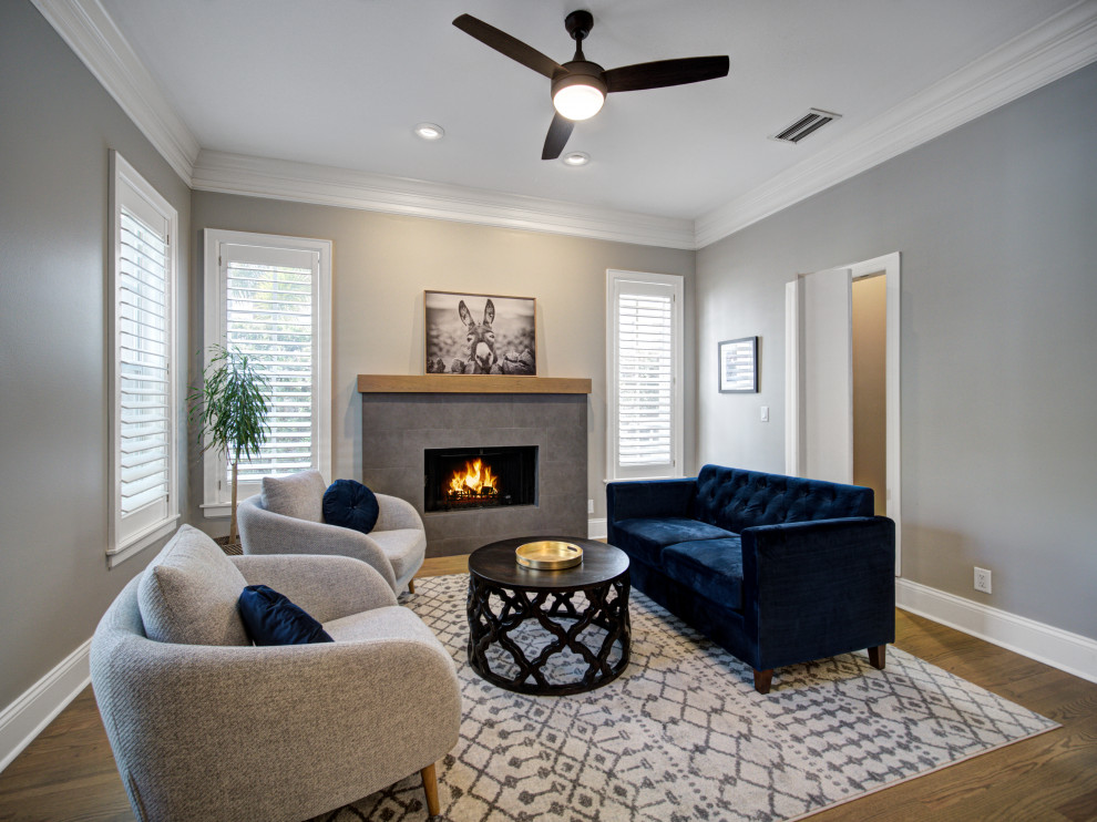 Example of a mid-sized trendy enclosed medium tone wood floor and brown floor family room library design in Tampa with gray walls, a standard fireplace, a stone fireplace and no tv