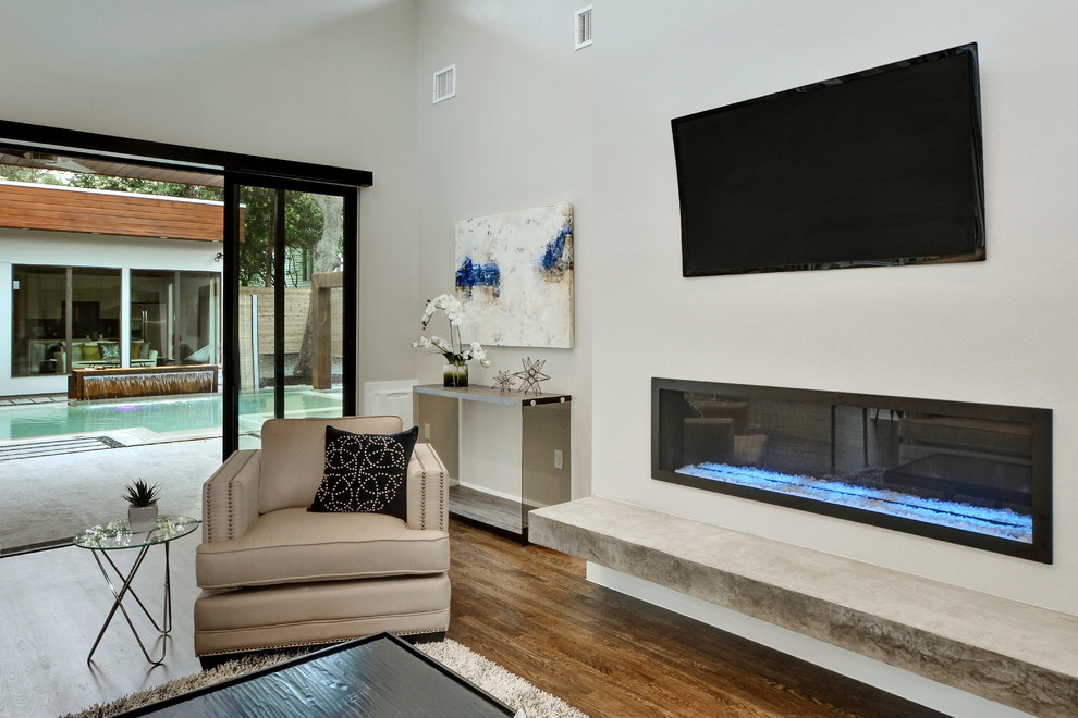 Inspiration for a large modern open plan games room in Austin with grey walls, medium hardwood flooring, a ribbon fireplace, a concrete fireplace surround and a wall mounted tv.