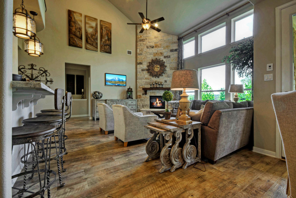Großes, Offenes Klassisches Wohnzimmer mit beiger Wandfarbe, braunem Holzboden, Eckkamin, Kaminumrandung aus Stein und TV-Wand in Austin