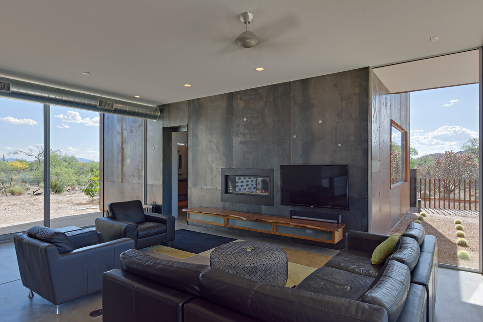 Foto de sala de estar abierta minimalista de tamaño medio con suelo de cemento, marco de chimenea de metal y televisor colgado en la pared