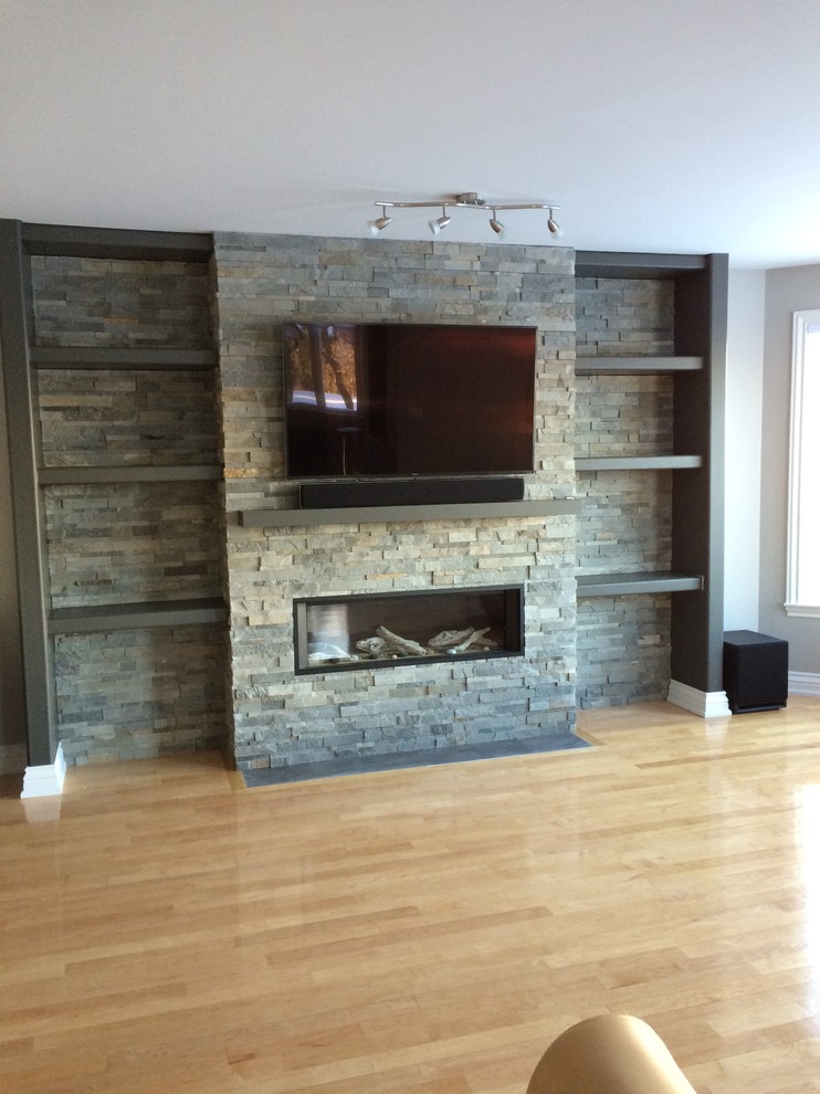 Mittelgroßes, Offenes Modernes Wohnzimmer mit grauer Wandfarbe, hellem Holzboden, Kamin, Kaminumrandung aus Stein, TV-Wand und braunem Boden in Ottawa