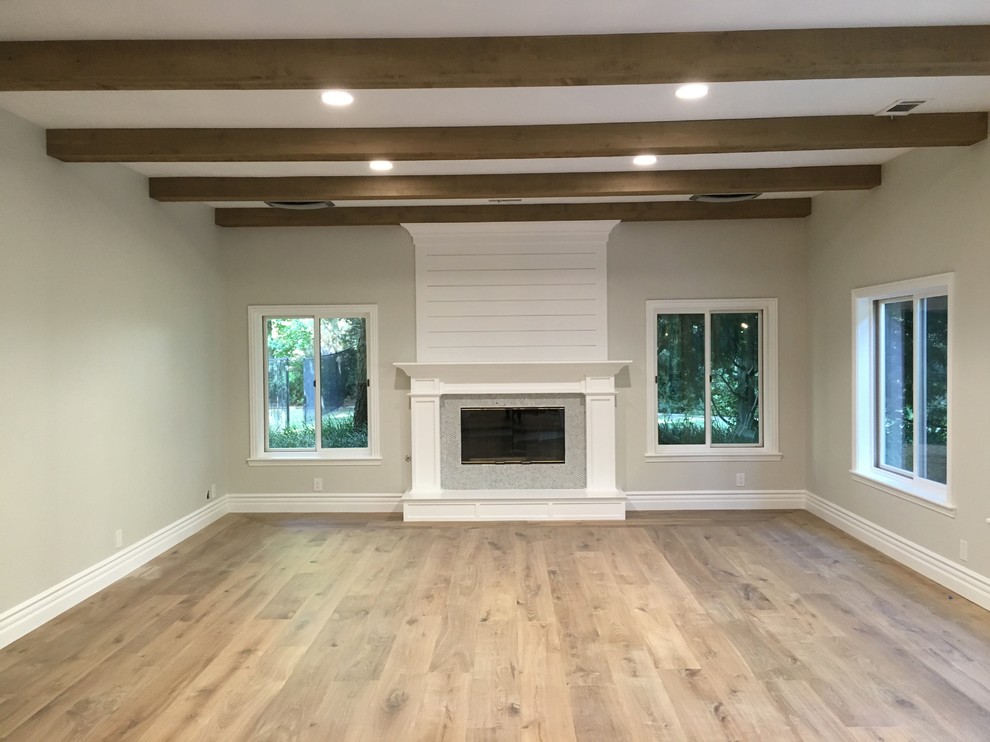 Family room - large cottage enclosed medium tone wood floor and brown floor family room idea in Los Angeles with gray walls, a standard fireplace and a stone fireplace