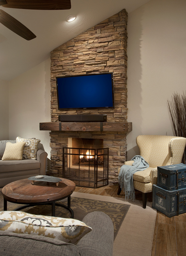 Imagen de sala de estar contemporánea de tamaño medio con paredes beige, suelo de madera en tonos medios, todas las chimeneas, marco de chimenea de piedra y televisor colgado en la pared