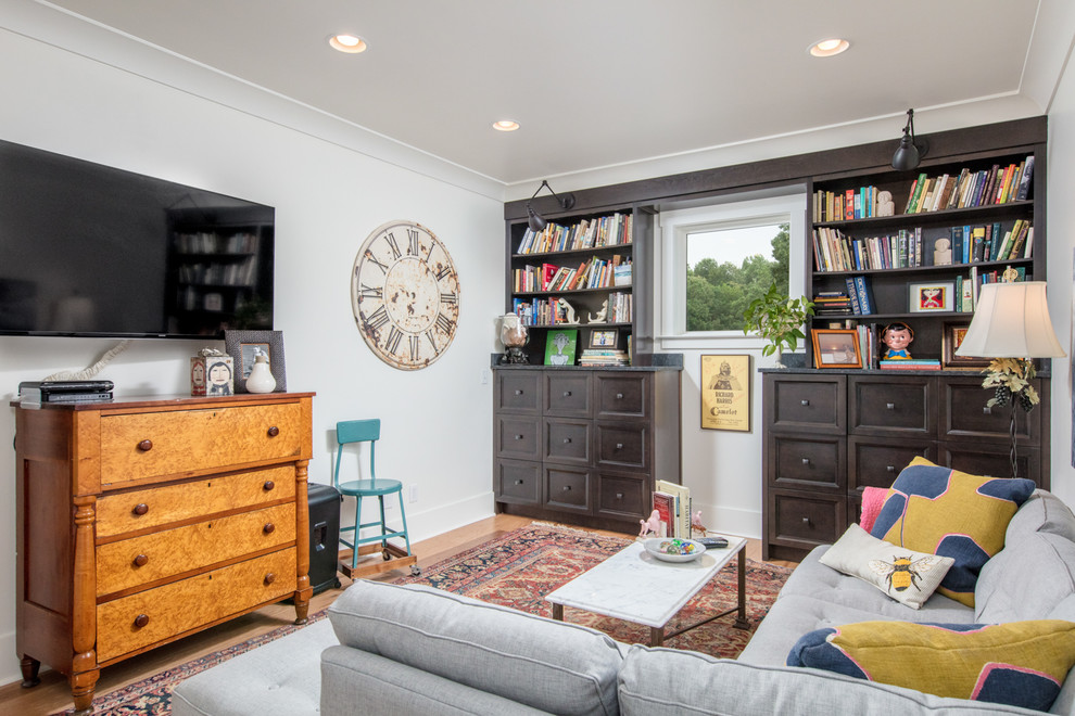 Esempio di un soggiorno chic chiuso con libreria, pareti bianche, pavimento in legno massello medio, TV a parete e pavimento marrone