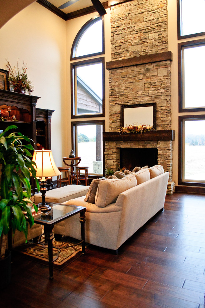 Living room - mid-sized rustic open concept dark wood floor living room idea in Oklahoma City with beige walls, a wall-mounted tv, a standard fireplace and a stone fireplace