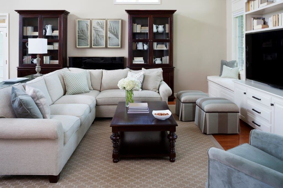 Imagen de sala de estar abierta clásica grande sin chimenea con paredes beige, suelo de madera en tonos medios y pared multimedia