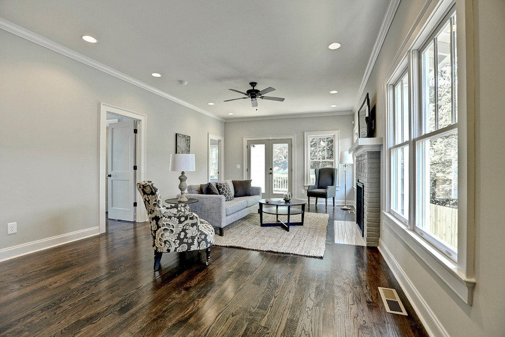 Großes, Offenes Klassisches Wohnzimmer mit grauer Wandfarbe, braunem Holzboden, Kamin, Kaminumrandung aus Backstein und TV-Wand in Atlanta