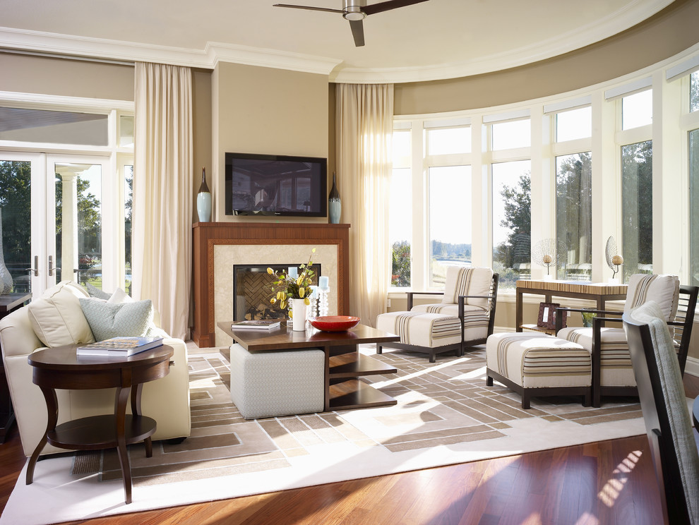 Cette image montre une salle de séjour design de taille moyenne et fermée avec un mur beige, un sol en bois brun, une cheminée standard, un téléviseur fixé au mur et un sol marron.