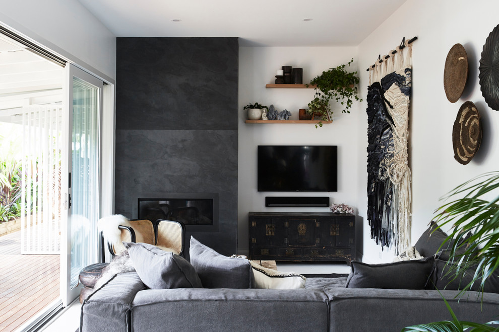 Mittelgroßes, Offenes Wohnzimmer mit weißer Wandfarbe, gebeiztem Holzboden, Kamin, Kaminumrandung aus Stein, weißem Boden und TV-Wand in Sydney
