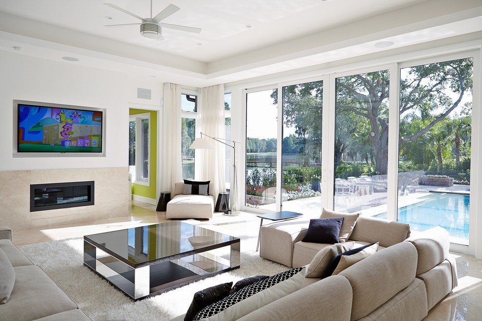 Mittelgroßes, Abgetrenntes Modernes Wohnzimmer mit weißer Wandfarbe, Gaskamin, TV-Wand, Travertin, Kaminumrandung aus Stein und beigem Boden in Tampa