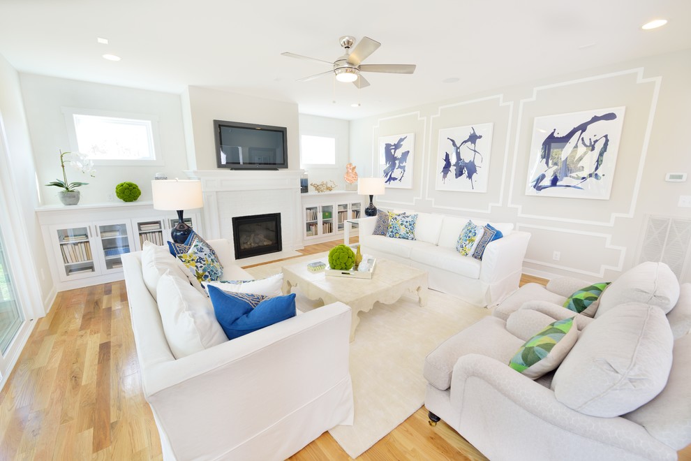 Immagine di un soggiorno costiero aperto con pareti beige, parquet chiaro, camino classico, TV a parete e tappeto