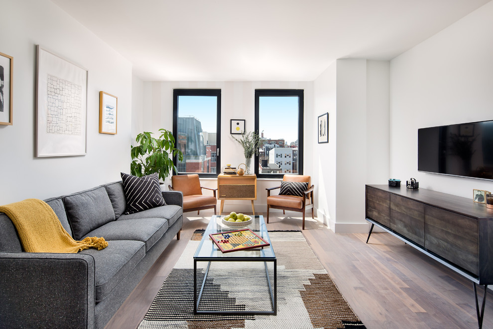 Esempio di un soggiorno moderno di medie dimensioni e aperto con pareti bianche, pavimento in legno massello medio e TV a parete
