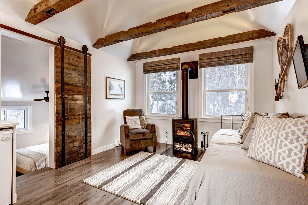 Esempio di un piccolo soggiorno country aperto con pareti grigie, pavimento in legno massello medio, TV a parete e stufa a legna