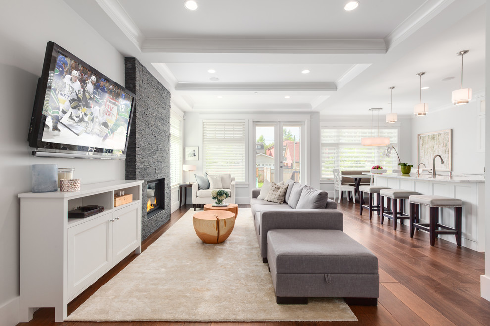 Example of a mid-sized transitional open concept family room design in Vancouver with gray walls, a standard fireplace, a stone fireplace and a wall-mounted tv