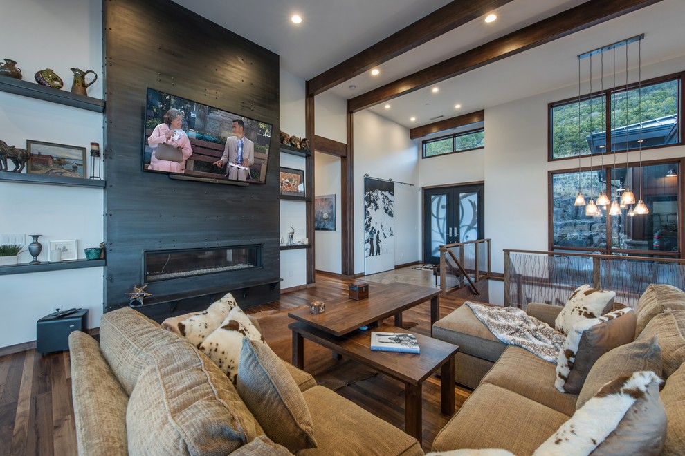 Inspiration for a contemporary open plan games room in Salt Lake City with white walls, a ribbon fireplace, a wall mounted tv, brown floors, dark hardwood flooring and a metal fireplace surround.