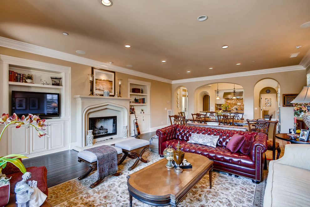 Großes, Offenes Klassisches Wohnzimmer mit beiger Wandfarbe, dunklem Holzboden, Kamin, Kaminumrandung aus Stein, braunem Boden und Multimediawand in San Diego