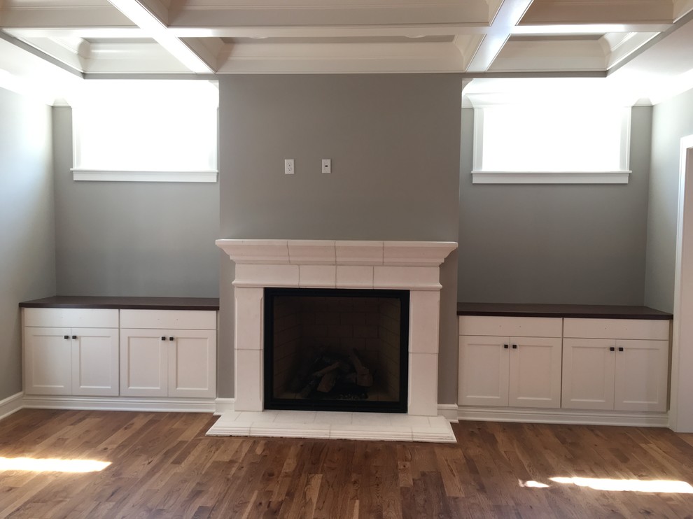 Cette photo montre une salle de séjour craftsman de taille moyenne avec un mur gris, parquet foncé, une cheminée standard et un manteau de cheminée en pierre.