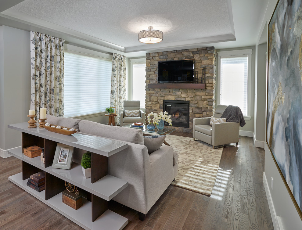 Photo of a large classic open plan games room in Edmonton with beige walls, light hardwood flooring, a standard fireplace, a stone fireplace surround, a wall mounted tv and feature lighting.