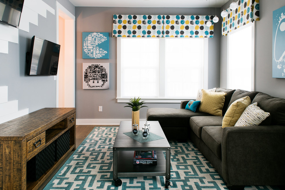 Foto de sala de estar tradicional renovada de tamaño medio con paredes grises, suelo de madera en tonos medios y televisor colgado en la pared