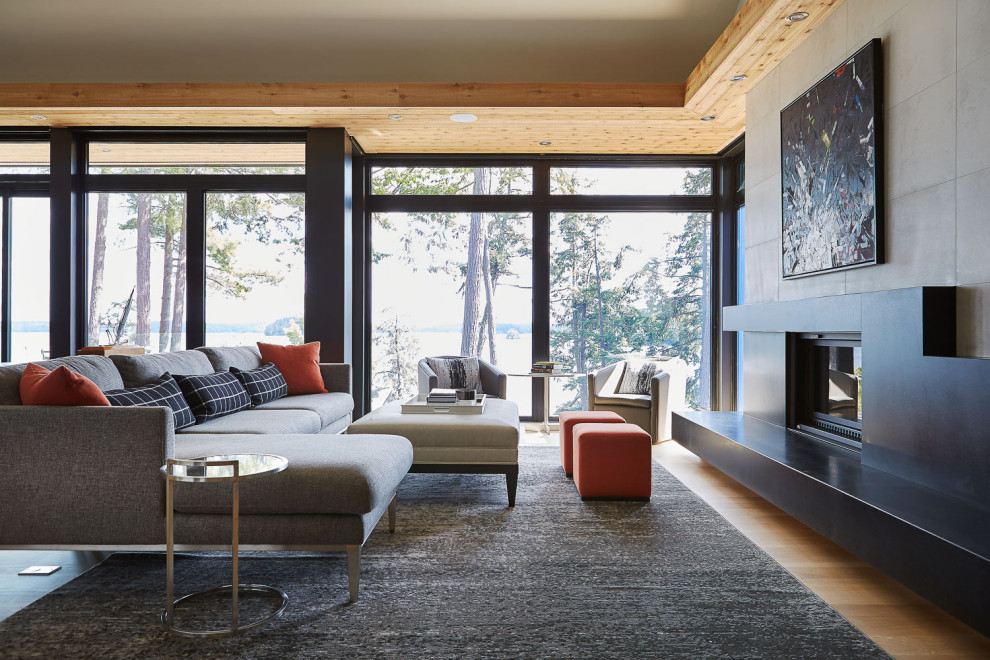 Cette image montre une grande salle de séjour design ouverte avec un mur gris, parquet clair, un poêle à bois, un manteau de cheminée en carrelage, un sol marron et un téléviseur encastré.