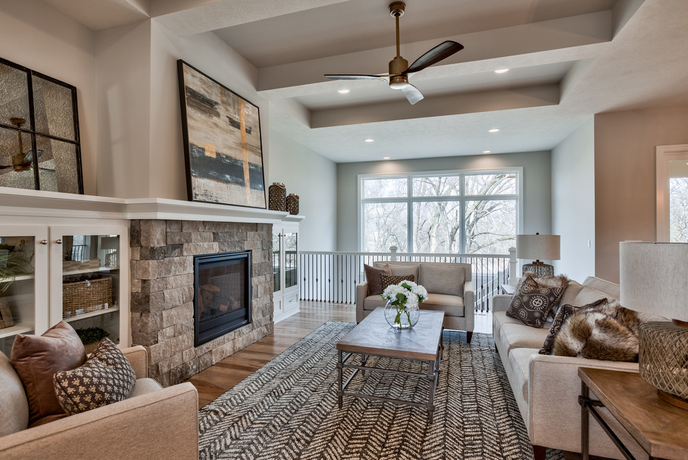 Offenes Klassisches Wohnzimmer mit grauer Wandfarbe, braunem Holzboden, Kamin, Kaminumrandung aus Stein und braunem Boden in Omaha