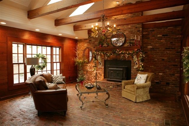 Foto de sala de estar cerrada rural de tamaño medio con paredes rojas, suelo de ladrillo, todas las chimeneas y marco de chimenea de ladrillo