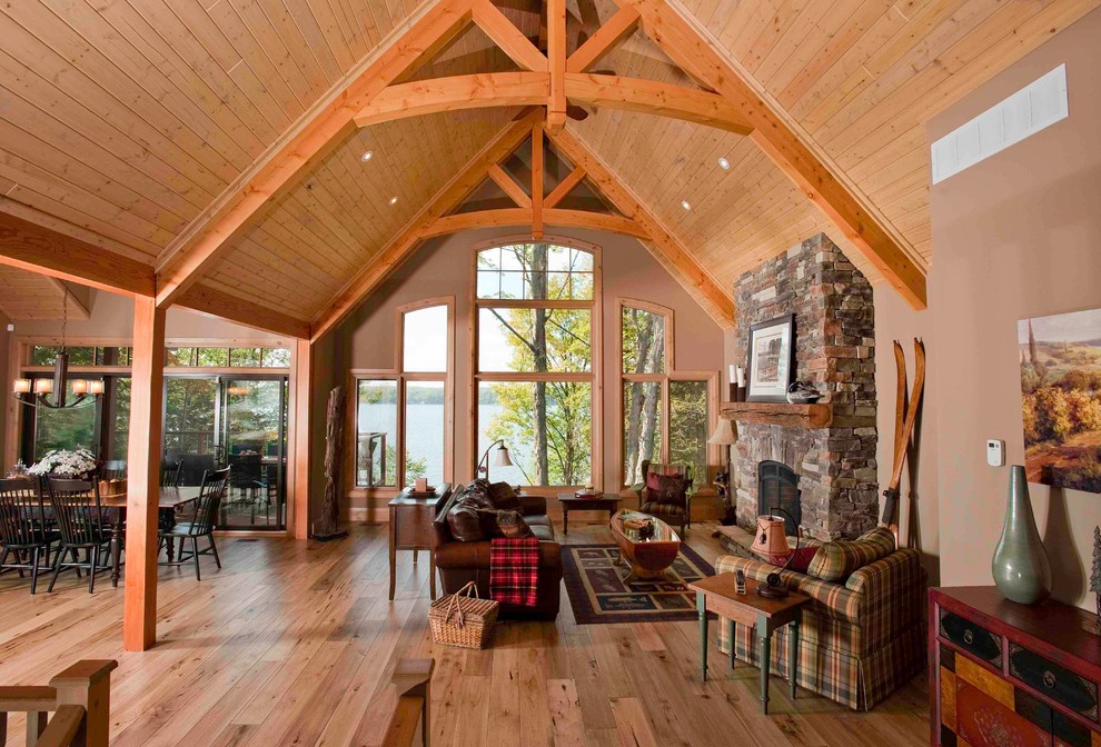 Foto de sala de estar abierta de estilo americano grande con paredes marrones, suelo de madera clara, todas las chimeneas y marco de chimenea de piedra
