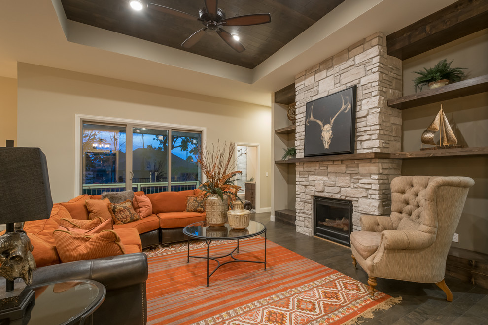 Mid-sized southwest open concept medium tone wood floor and brown floor game room photo in Other with beige walls, a standard fireplace, a stone fireplace and a wall-mounted tv