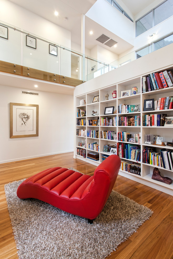 Esempio di un soggiorno contemporaneo con libreria, pareti bianche, pavimento in legno massello medio e tappeto