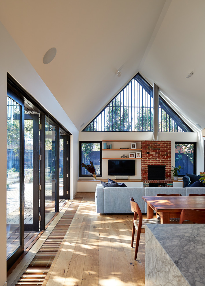 Offenes Modernes Wohnzimmer mit weißer Wandfarbe, hellem Holzboden, TV-Wand, braunem Boden und Kamin in Melbourne