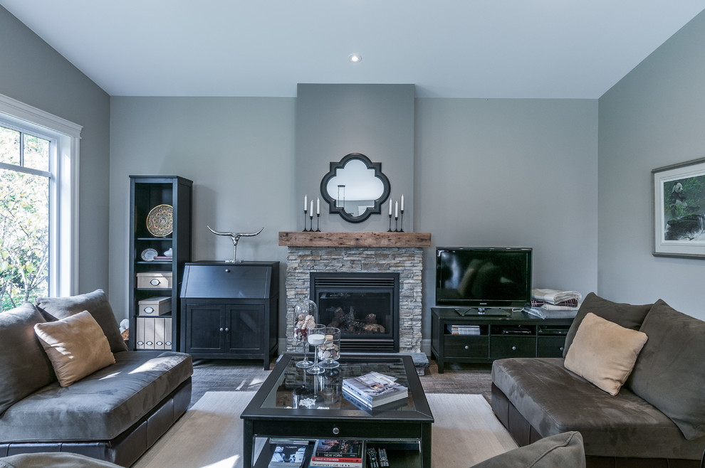 Exemple d'une grande salle de séjour craftsman ouverte avec un mur gris, parquet foncé, une cheminée standard, un manteau de cheminée en pierre et un téléviseur indépendant.