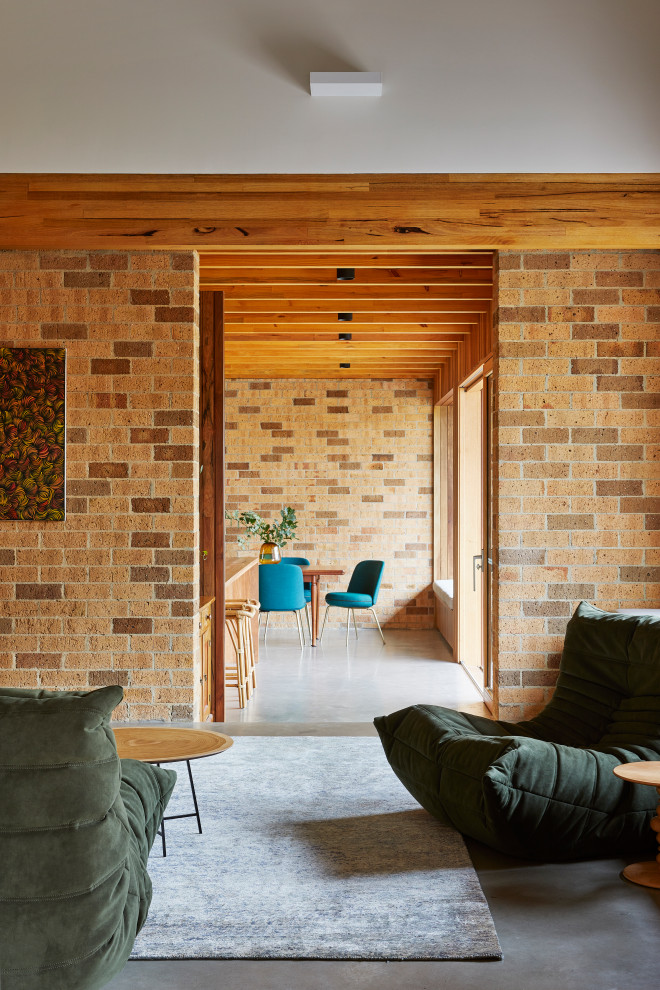 シドニーにあるカントリー風のおしゃれな独立型ファミリールーム (茶色い壁、コンクリートの床、グレーの床、レンガ壁) の写真