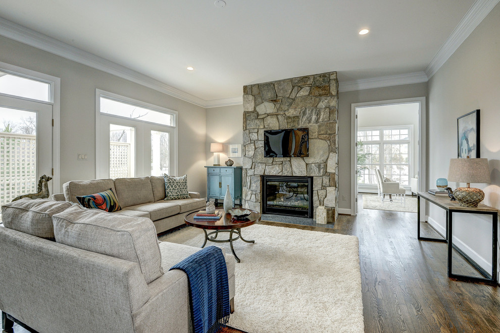 Example of a mid-sized transitional open concept medium tone wood floor and brown floor family room design in DC Metro with a standard fireplace, a stone fireplace, a wall-mounted tv and beige walls