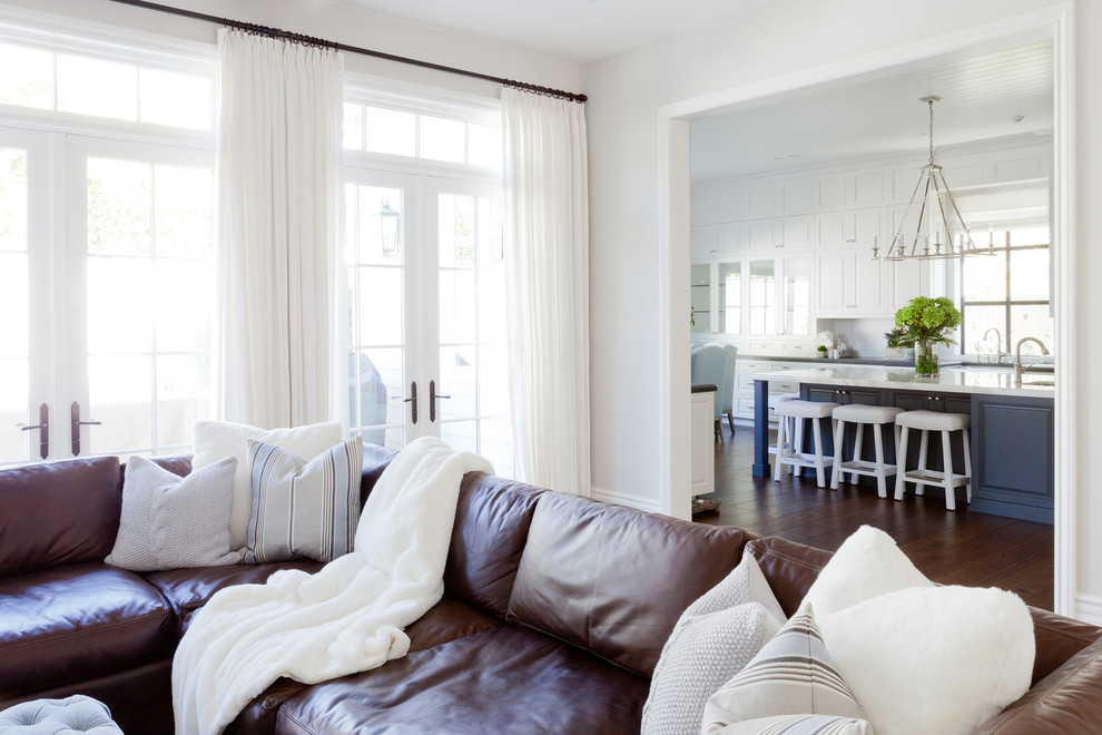 Cette image montre une très grande salle de séjour traditionnelle avec un mur blanc, un sol en bois brun et un téléviseur encastré.