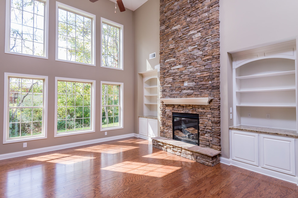 Cette image montre une salle de séjour traditionnelle ouverte avec un mur beige, un sol en bois brun, une cheminée standard et un manteau de cheminée en pierre.