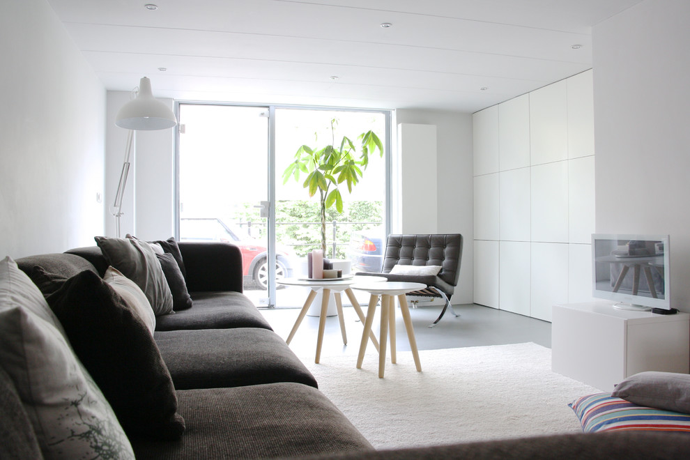 Exempel på ett modernt allrum, med vita väggar, en fristående TV och grått golv