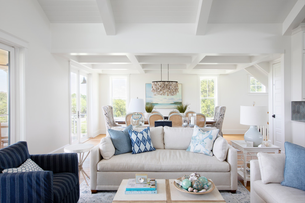 Offenes Maritimes Wohnzimmer mit weißer Wandfarbe, hellem Holzboden, Kamin, gefliester Kaminumrandung, TV-Wand und freigelegten Dachbalken in Charleston