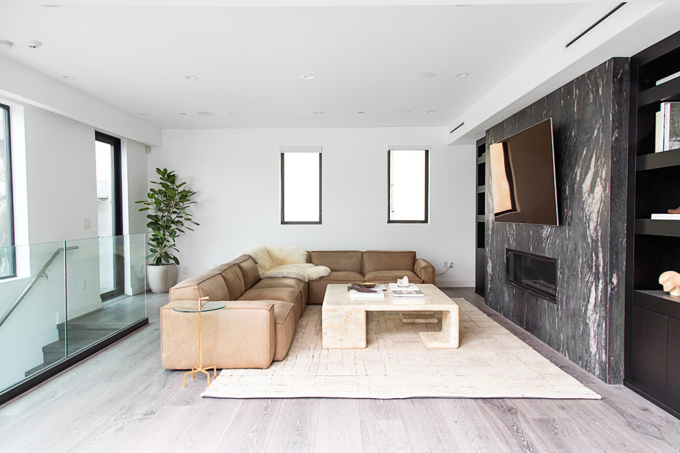 Inspiration for a contemporary mezzanine games room in Los Angeles with white walls, light hardwood flooring, a ribbon fireplace, a stone fireplace surround, a wall mounted tv and beige floors.