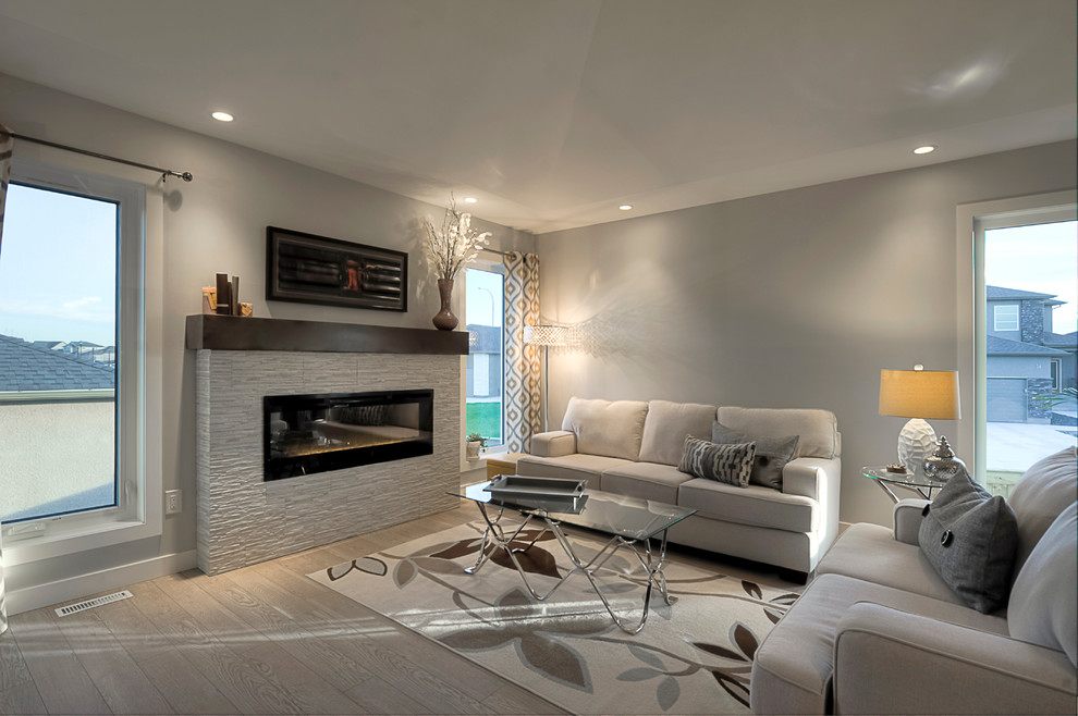 Modelo de sala de estar abierta clásica renovada grande con paredes grises, suelo laminado, todas las chimeneas, marco de chimenea de piedra y suelo gris