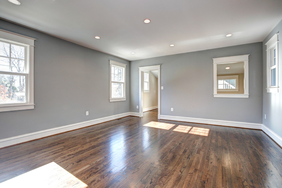 Ejemplo de sala de estar abierta de estilo americano de tamaño medio sin chimenea con paredes grises y suelo de madera en tonos medios