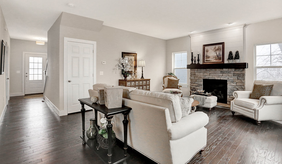 Imagen de sala de estar abierta clásica de tamaño medio con paredes beige, suelo de madera oscura y todas las chimeneas