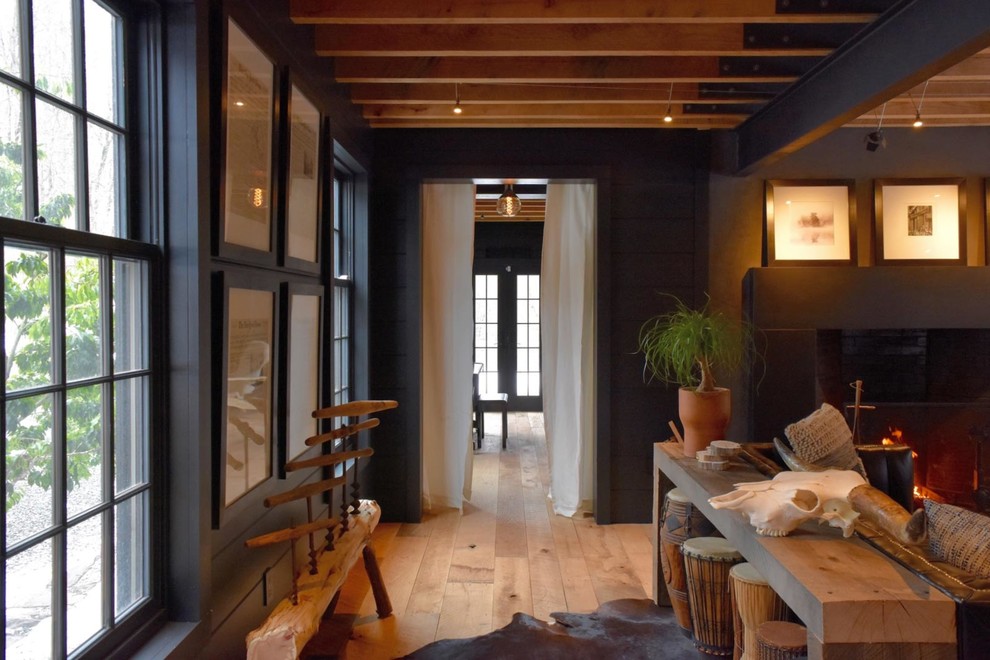 Diseño de sala de estar abierta urbana grande con paredes negras, suelo de madera en tonos medios, todas las chimeneas y marco de chimenea de hormigón