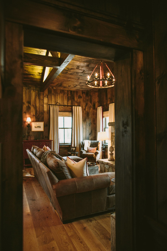 Aménagement d'une salle de séjour montagne de taille moyenne et ouverte avec un mur marron, un sol en bois brun, une cheminée standard, un manteau de cheminée en pierre et aucun téléviseur.